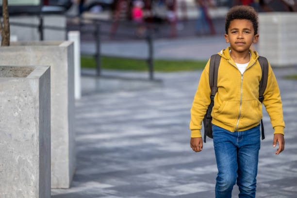 istock Curly-haired schoolboy with a backpack walking in the street 1689066815