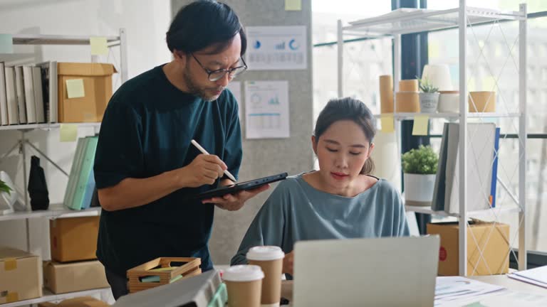 Creative young asian professionals discussing about their work in front of their laptop at home office