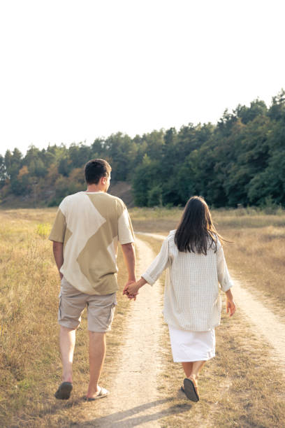 istock A man and a woman walk into a field holding hands. 1689081816