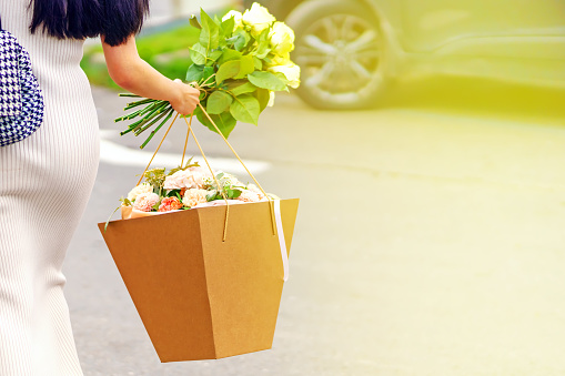 Graceful girl carries bouquets of flowers to the car for a gift