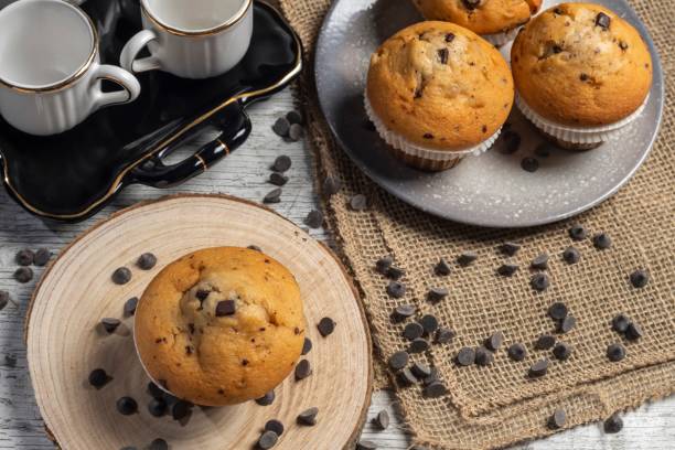 istock Muffin or cupcake with chocolate chips on wooden table background. Concept of making industrial or homemade pastries. 1689099505
