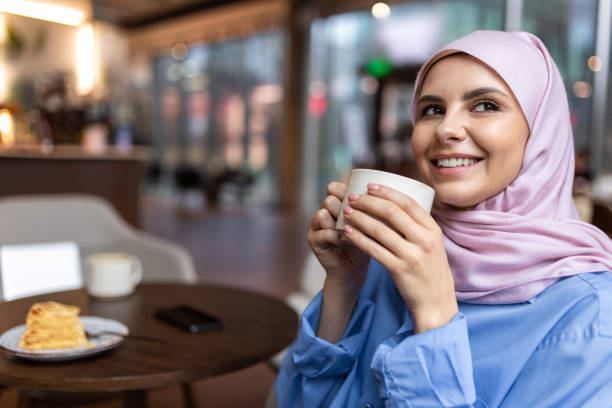 istock Woman in pink hijab drinking coffee and smiling 1689100708