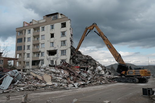 Deconstruction of a  building, excavator with grabber takes parts of building bit by bit