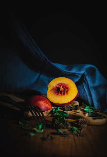 close-up of mothball fruit on wooden table with green leaves and blue cloth in the background, with sidelight, copy space