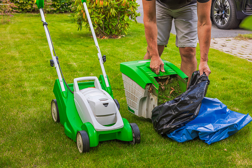 Close-up view of man working with electric lawn mower. Season garden working concept.