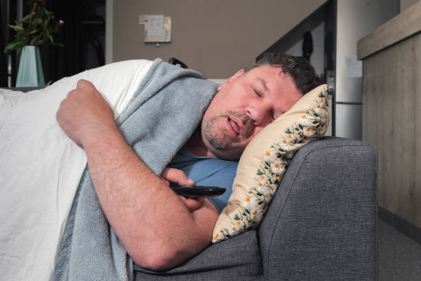 istock Sleeping middle aged man with tv remote in living room 1689124210