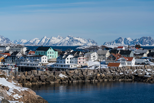 Port of fishing village Henningsvær in the Lofoten Island. On sunny winter day against rocky mountain.