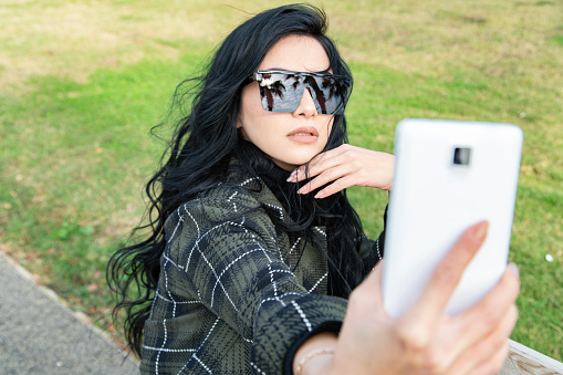 Woman with sunglasses making selfie on smartphone