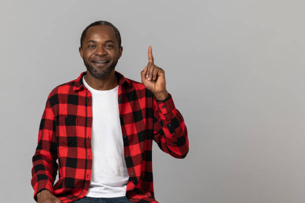istock Satisfied black bearded man wearing red checkered shirt pointing upwards 1689151628