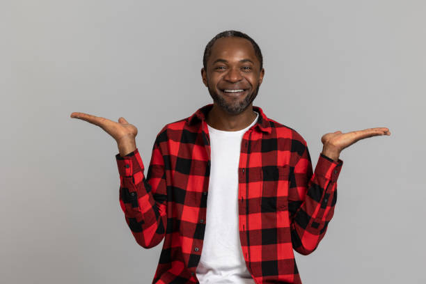 istock Joyful black bearded man wearing red checkered shirt presenting copy space on palms 1689151631