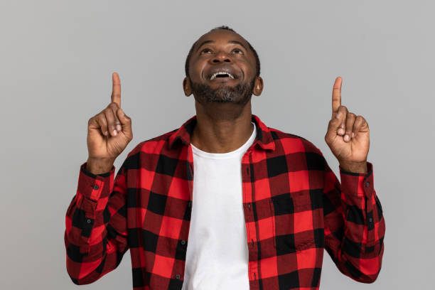istock Satisfied black bearded man wearing red checkered shirt pointing upwards 1689151652