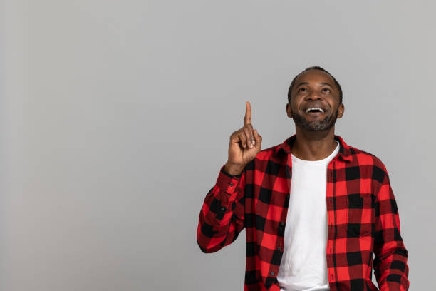 istock Cheerful black bearded man wearing red checkered shirt pointing up at copy space for advertisement 1689151665