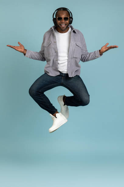 istock Bearded dark skinned man in headphones dancing making movements to music jumping copy space 1689152190