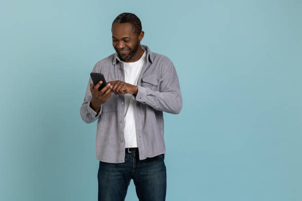 istock Joyful black man wearing gray shirt using mobile phone 1689152754