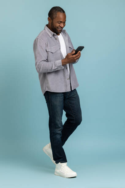 istock Full length of black man wearing gray shirt using samrtphone 1689152768