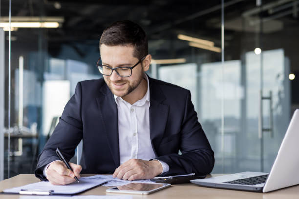 istock Young businessman working in the office at the workplace with documents, signing an agreement, working with account 1689159417