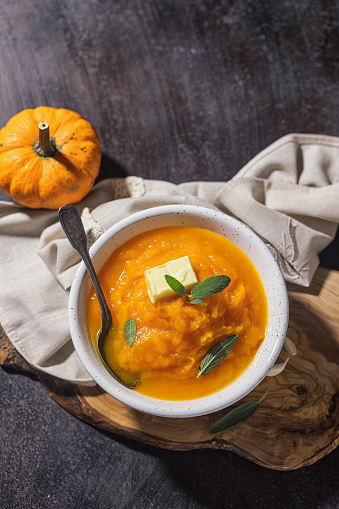 Homemade pumpkin cream soup with sage on a rustic background