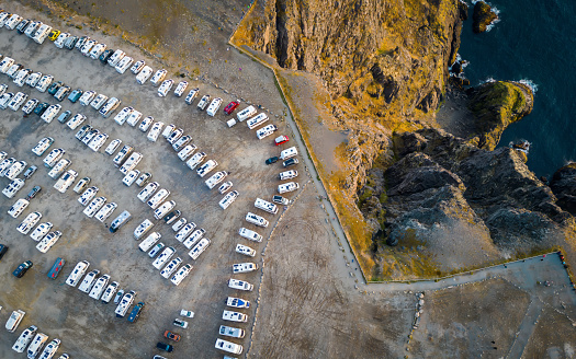 Caravan parking lot filled with campervans with travellers seen from above at the edge of the North Cape in Norway