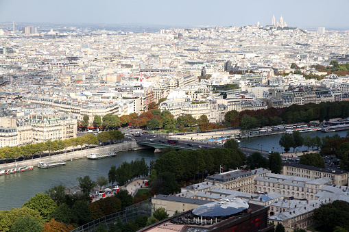 Color DSLR view of the Eiffel Tower and one of the replicas of the Statue of Liberty, Paris, France.  The image has the Seine River flowing in the foreground and a blue sky background.  Though there are no people in the image, it is a popular tourist destination.  The image is in vertical orientation with copy space for text.  