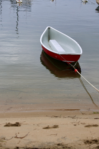 Red row boat tethered to the beach at low tide