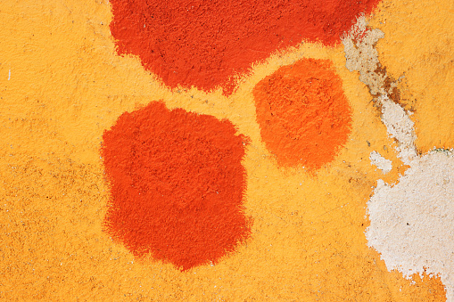 Texture of old house concrete wall painted into deep Vibrant warm golden yellow color with orange spots and cracks on the surface. Decorative plaster. Abstract design grunge background. Copy space