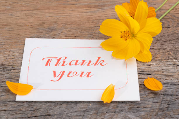 istock Thank you note with bright yellow flowers on a wooden table. 1689196234