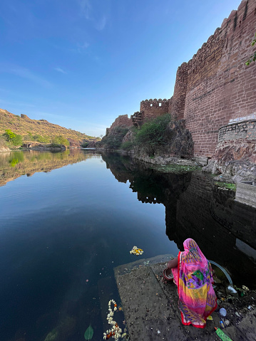 Stock photo showing Jodhpur's Mehrangarh Fort sandstone walls surrounded by the fort's water system which is used for washing clothes by local people.