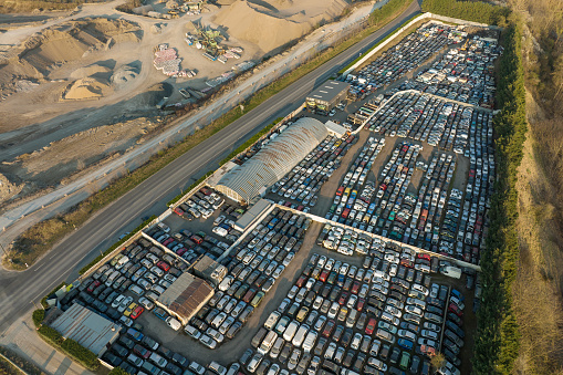 Aerial view of big parking lot of junkyard with rows of discarded broken cars. Recycling of old vehicles.