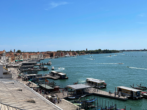 Venice, Italy - July 14, 2023: Stock photo showing close-up view of  tourists and locals visiting the Riva degli Schiavoni with moored boats at Venice lagoon waterfront wooden jetties, Venice, Italy.