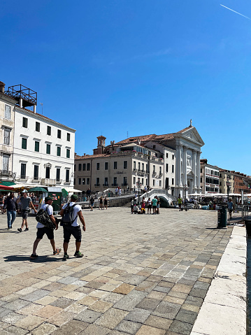 Venice, Italy - July 14, 2023: Stock photo showing close-up view of  tourists and locals walking along the Riva degli Schiavoni, Venice, Italy.
