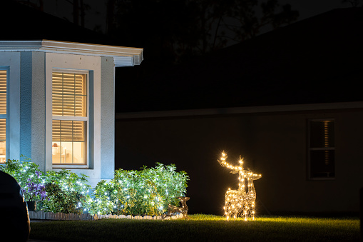 Brightly illuminated christmas decorations on front yard of florida family home. Outside decor for winter holidays