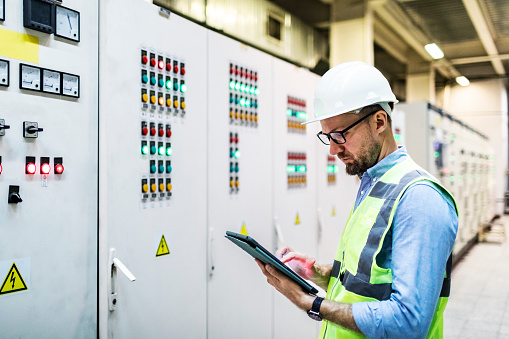 Electrical engineer working in control room. Electrical engineer checking Power Distribution Cabinet in the control room