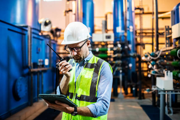 Ingegnere elettrico che esamina la centrale elettrica utilizzando tablet digitale e walkie-talkie - foto stock