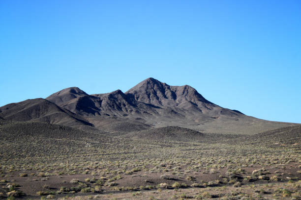 Color landscape photograph of a hill range deep in the rural Nevada desert with a bright vibrant sky above with with copy space.