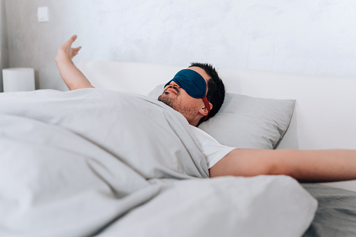 As the world continues outside, the young man, equipped with his eye mask, relishes the comfort and peacefulness of his bed