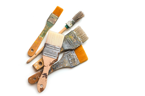 Four used brushes for paint, lacquer, varnish and stain isolated with shadows on a white background, copy space, top view from above, selected focus