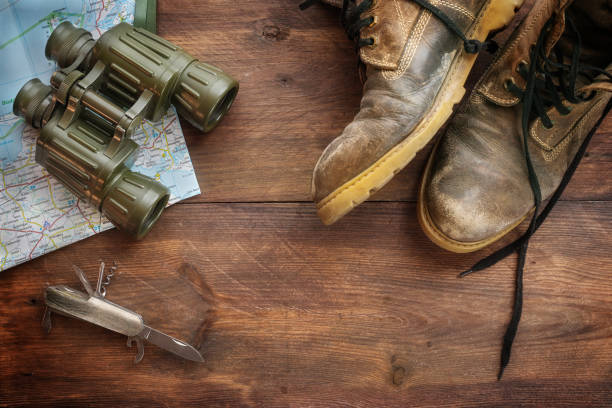 istock Old leather trekking boots, binoculars, map and a pocket knife on dark rustic wood, concept for travel, hiking and adventure holidays, high angle view from above, copy space 1689314165