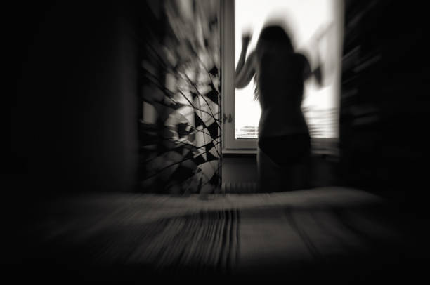 Woman in despair in front of window, black and white motion blur.