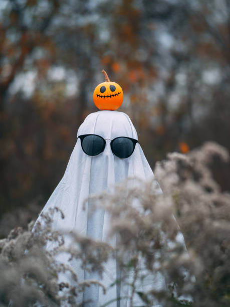 istock Halloween ghost costume with sunglasses. Cheerful pumpkin on the head. Ghost bed sheet 1689373433