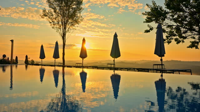 SLO MO Beautiful Infinity Pool at Holiday Resort under Orange Sky at Sunset in Countryside