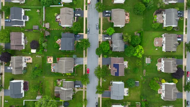 Large American neighborhood. Top down aerial shot above road in residential neighborhood with houses and homes in summer.