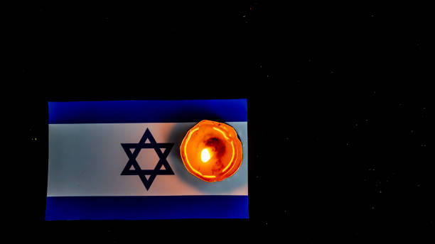 istock Israeli flag and candles burning above it, Holocaust memory day 1689492706