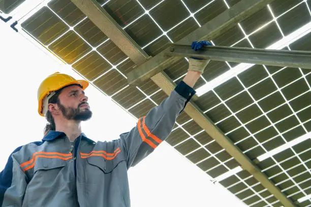 Factory engineer man checking and repairing solar panel construction. Worker works at solar farm for renewable energy. Solar cell industry for sustainability.