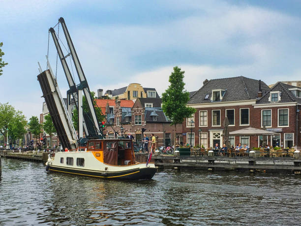 Leidschendam, netherlands - May 29 2016: a boat with dutch flag is floating on the water of a canal leaving a small village
