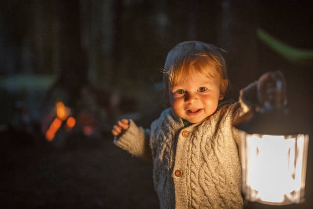istock Charming toddler holding a lantern on camping at night. 1689651460