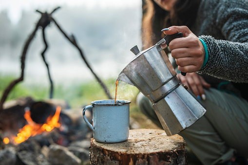 Young woman having morning coffee on camping in the nature.