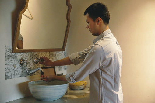 Close up shot of business man washing hands under running water at public restroom