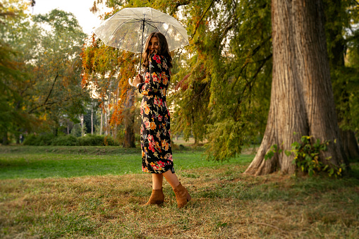 Full body shot, vogue style photo of girl posing in park with translucent umbrella