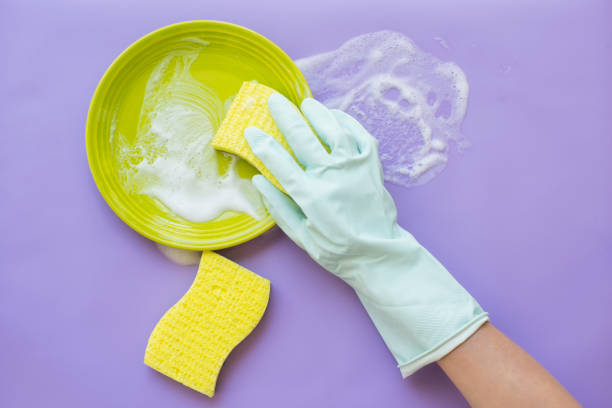 istock a gloved hand washes a plate. posky top view on a lilac background. 1689702920