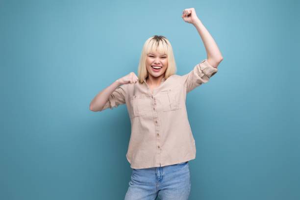 istock cheerful blond young woman in shirt on studio blue background 1689712918